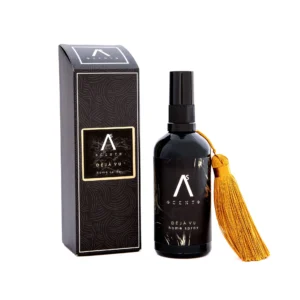 Déjà Vu home spray bottle with an orange tassel next to a black patterned box on a white background